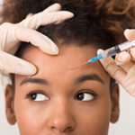 African-american woman getting botox injection in forehead